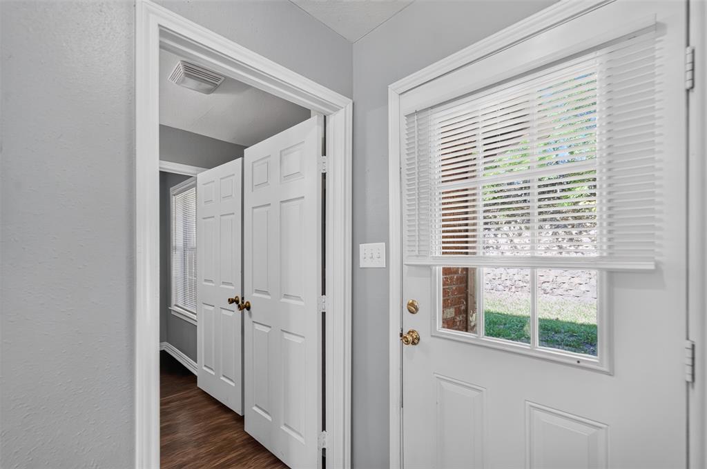 Entryway featuring wood-finish flooring, white paneled doors, and a door with an inset glass window and integrated blinds