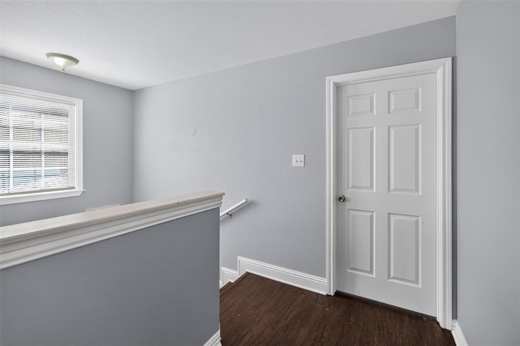 Six-panel interior door, wood-finish flooring, neutral wall paint, flush-mount light fixture, and window with blinds