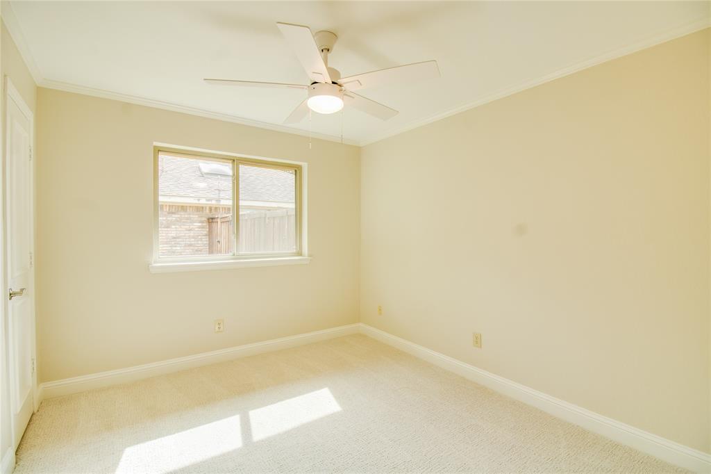 Neutral-toned room featuring wall-to-wall carpeting, a multi-blade ceiling fan with integrated lighting, a sliding window with a cream frame, and a solid-core interior door