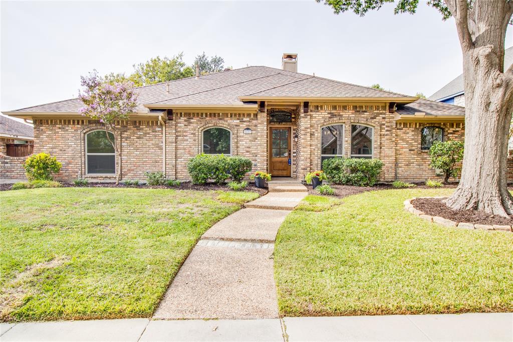 Brick exterior featuring arched window casings, a wood-framed front entry, hipped roofline, and aggregate concrete walkway