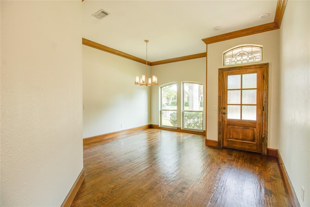 Entryway featuring wood-finish flooring, high ceilings with crown molding, a multi-pane wood door with an arched transom window, and a chandelier
