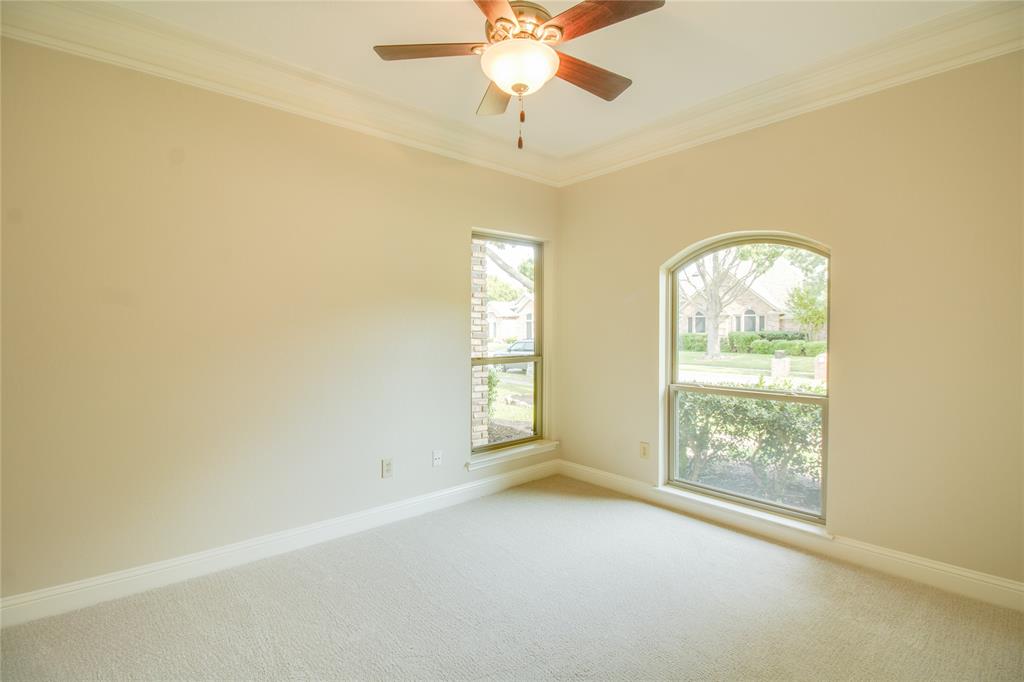 Neutral interior featuring crown molding, neutral carpeting, a central ceiling fan with integrated lighting, and an arched window