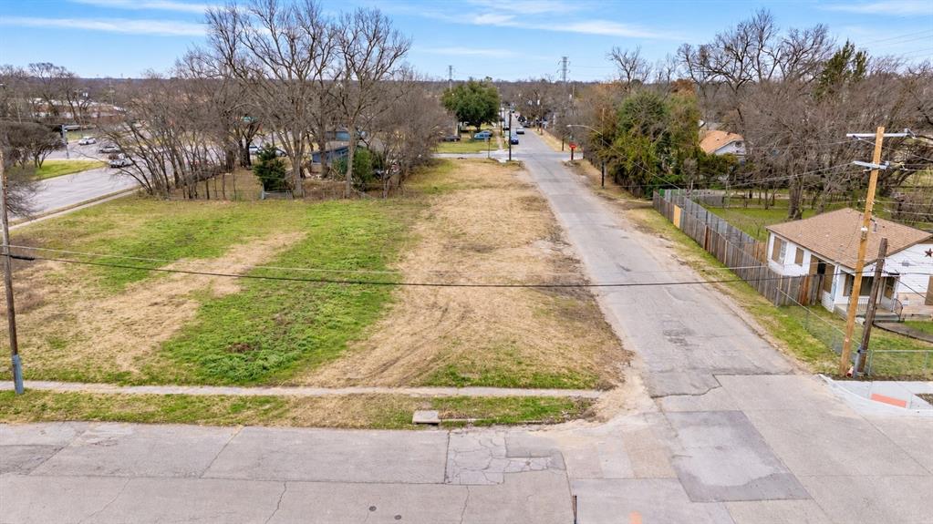 Expansive cleared corner lot featuring mature trees, paved street frontage, and established concrete sidewalk Expansive cleared corner lot featuring mature trees, paved street frontage, and established concrete sidewalk
