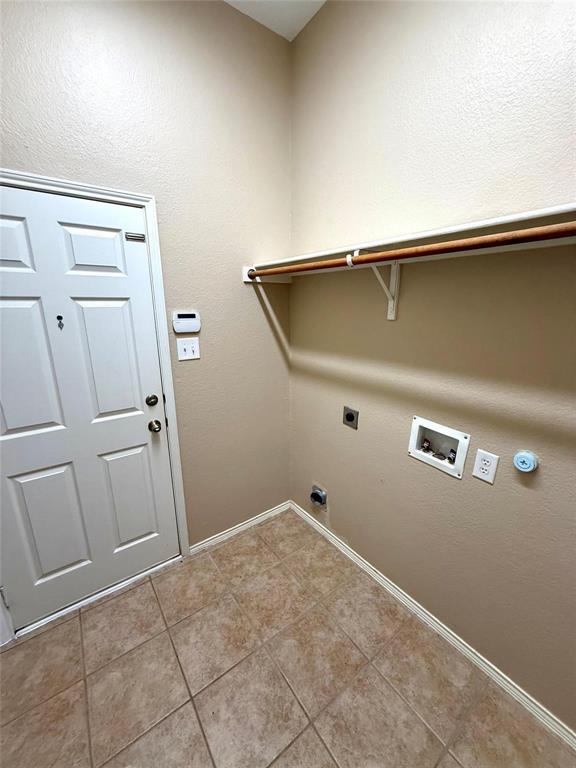 Utility space featuring ceramic tile flooring, a six-panel door, and a built-in shelf with a clothes hanging rod Utility space featuring ceramic tile flooring, a six-panel door, and a built-in shelf with a clothes hanging rod