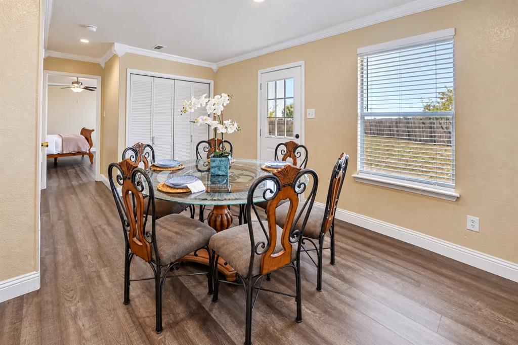 Wood-finish flooring, crown molding, double-door closet with louvered panels, and a glass-paneled exterior door