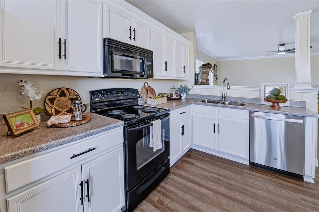 Kitchen featuring white shaker-style cabinetry with matte black hardware, stone-finish countertops, black electric range, stainless steel dishwasher, and wood-finish flooring