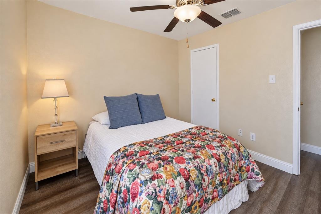 Neutral-toned walls featuring wood-finish flooring, a ceiling fan with integrated lighting, and a single-panel interior door