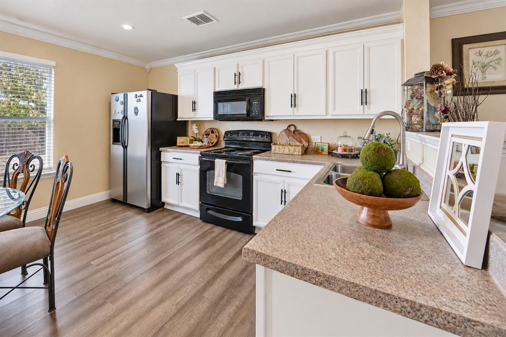 Kitchen featuring white shaker-style cabinetry, wood-finish flooring, solid surface countertops, and black built-in appliances
