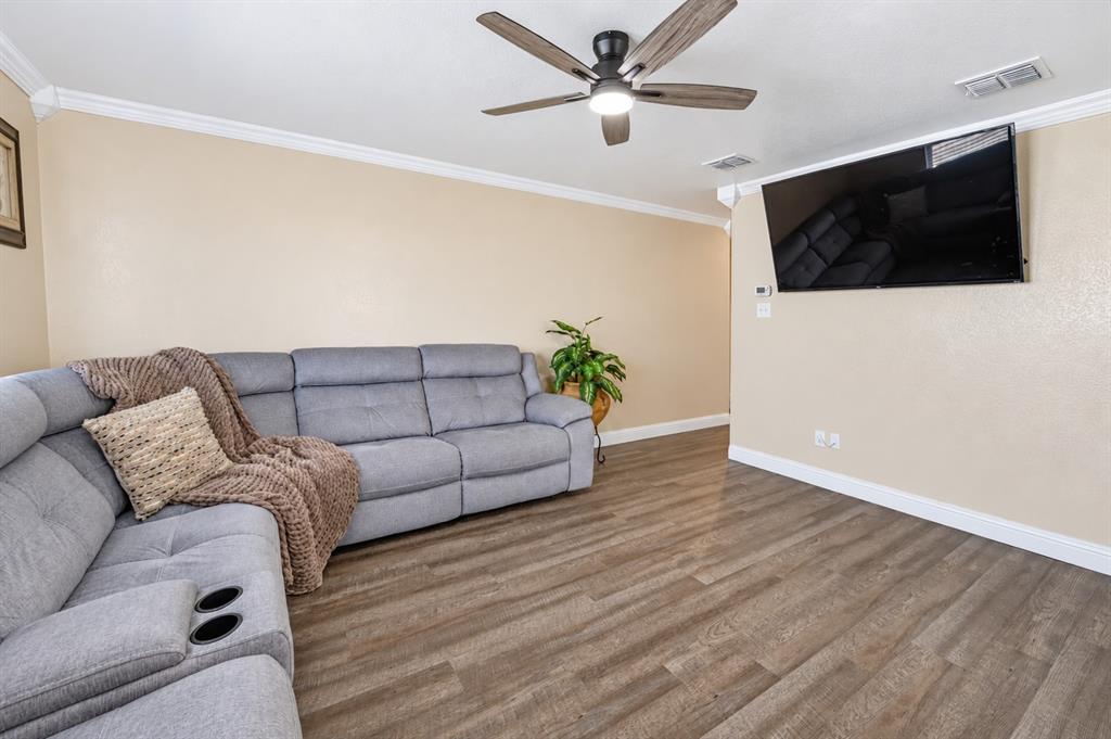 Room featuring wood-finish flooring, crown molding, and a ceiling fan with integrated lighting