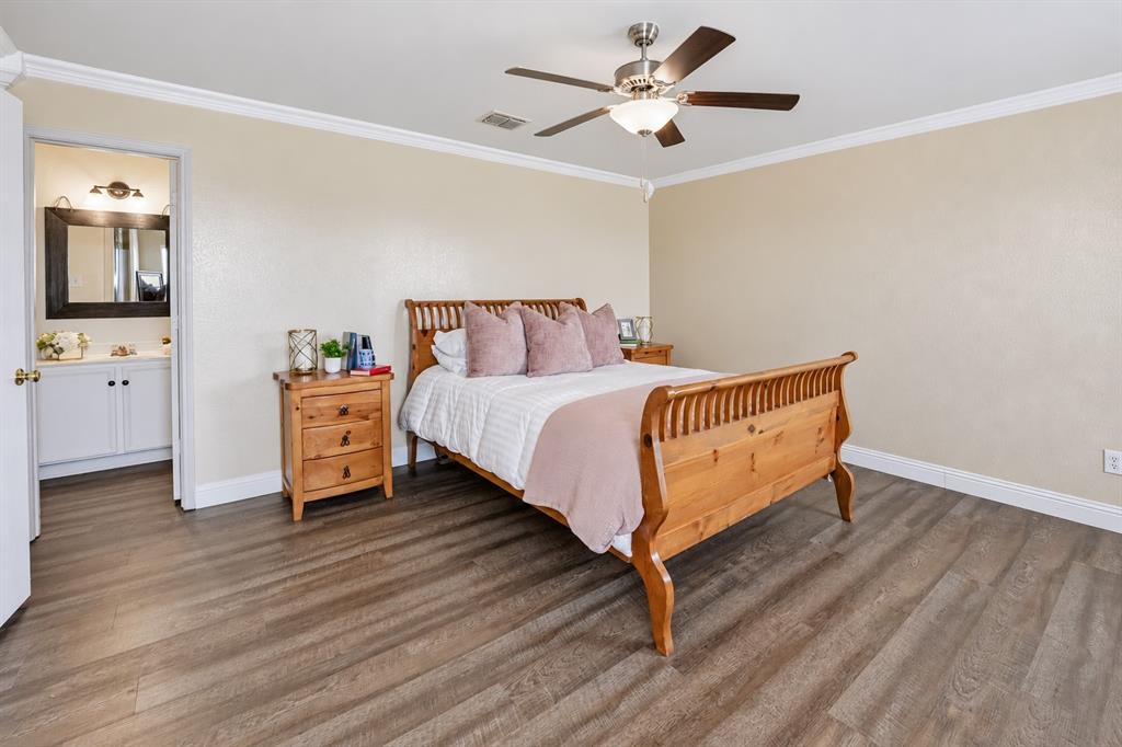 Room featuring wood-finish flooring, crown molding, and a ceiling fan with integrated light fixture