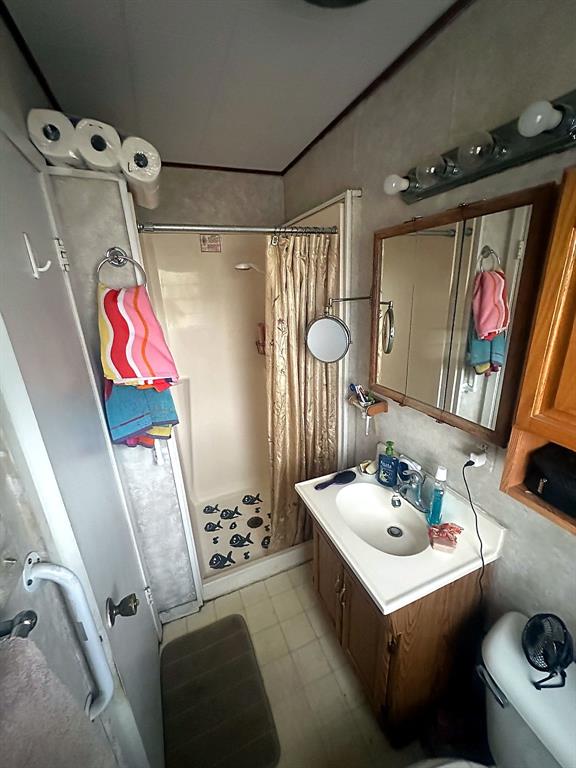 Bathroom featuring a vanity with wood-finish cabinetry, integrated sink, and wall-mounted medicine cabinet with mirror, complemented by a molded shower enclosure and multi-bulb vanity light fixture