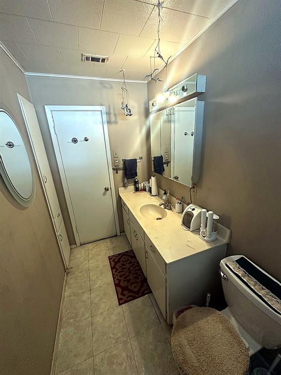 Extended vanity with integrated countertop and sink, wall-mounted mirrored medicine cabinet, built-in cabinetry, and tile flooring