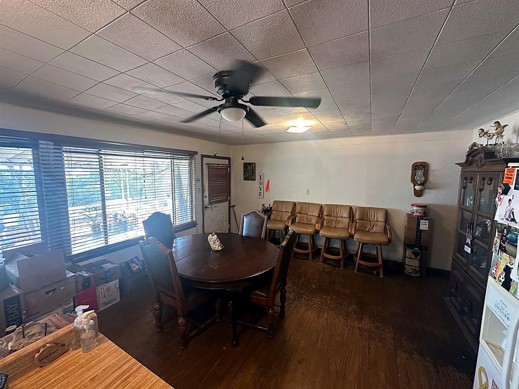 Spacious room featuring wood-finish flooring, a ceiling fan, and large windows with horizontal blinds
