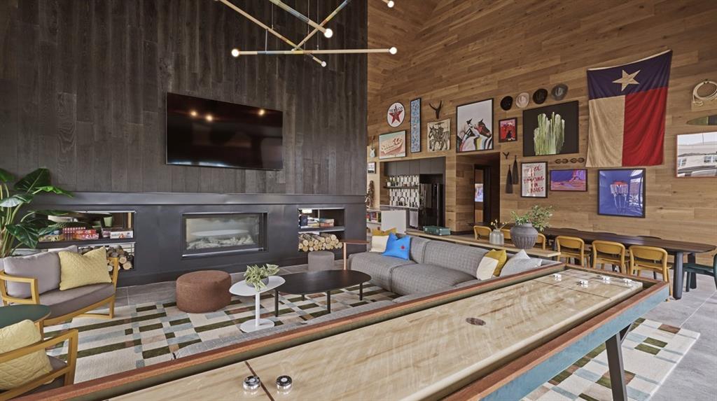 Living room featuring a high ceiling, wood walls, a chandelier, a fireplace, and tile patterned floors