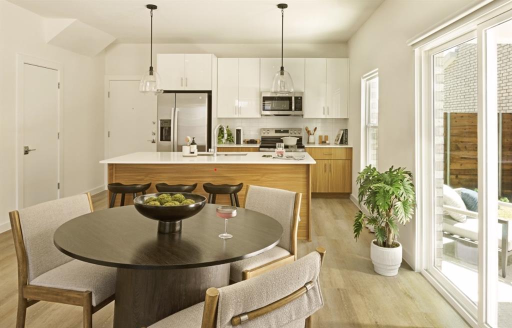 Kitchen featuring stainless steel appliances, light wood finished floors, tasteful backsplash, a center island with sink, and light countertops Kitchen featuring stainless steel appliances, light wood finished floors, tasteful backsplash, a center island with sink, and light countertops