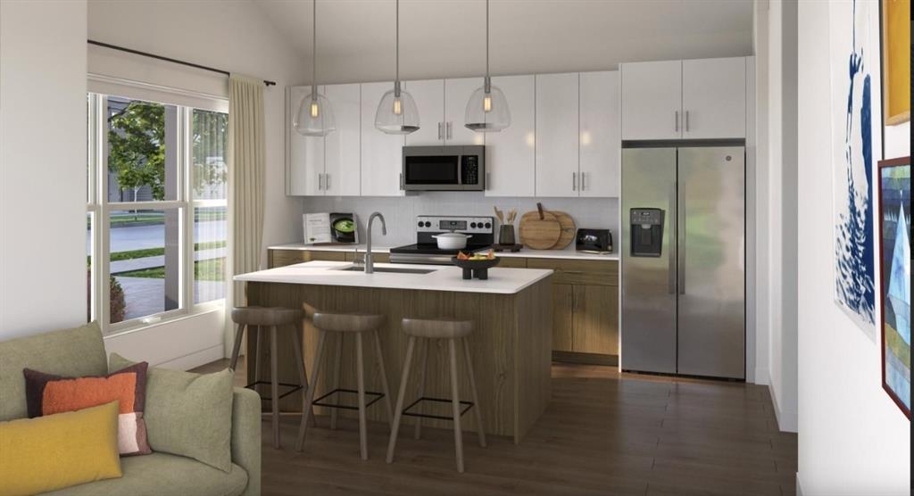 Kitchen with stainless steel appliances, a breakfast bar, white cabinets, hanging light fixtures, and open floor plan Kitchen with stainless steel appliances, a breakfast bar, white cabinets, hanging light fixtures, and open floor plan