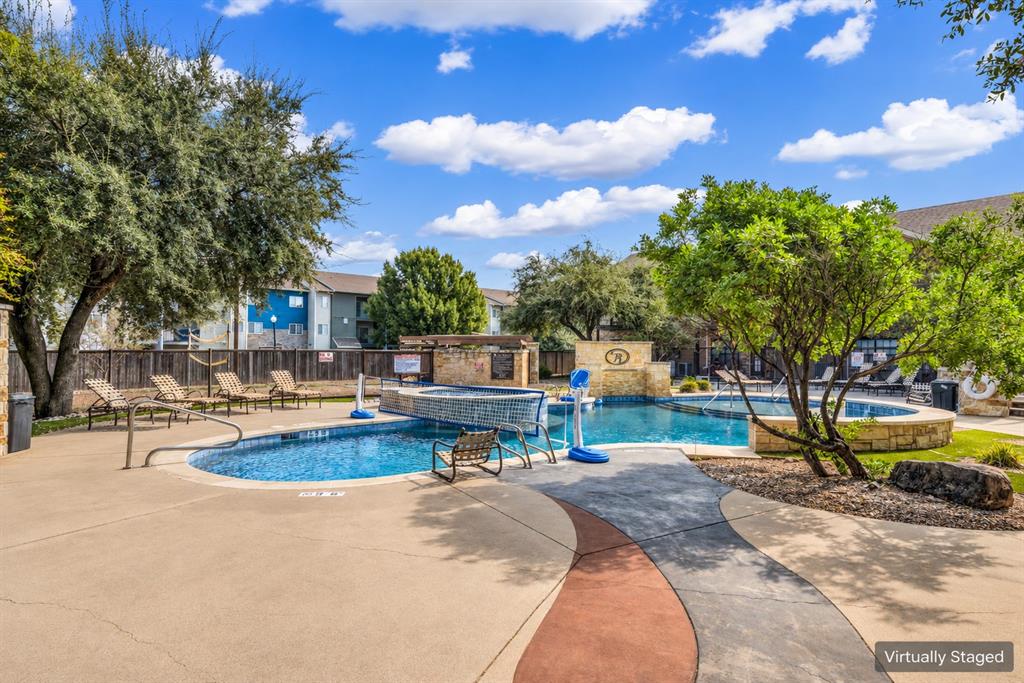 In-ground pool featuring a stone water feature, attached spa, concrete decking, and perimeter privacy fencing In-ground pool featuring a stone water feature, attached spa, concrete decking, and perimeter privacy fencing