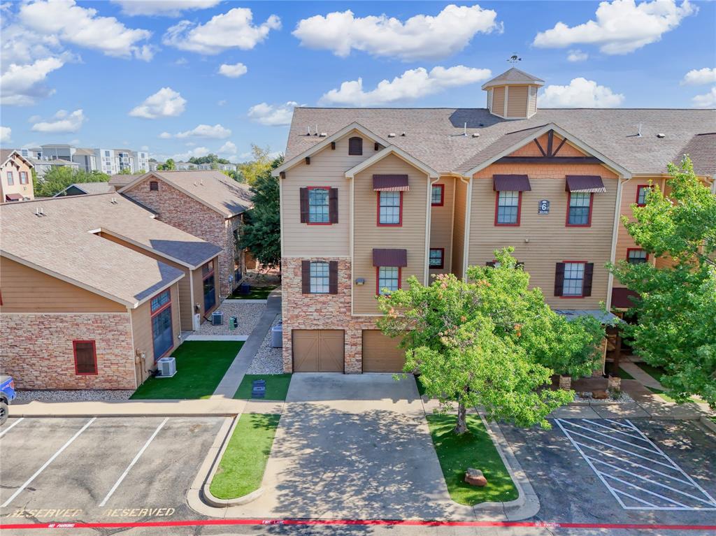 Multi-story exterior featuring a mix of horizontal lap siding and masonry stone veneer, dual attached garages, a shingled roof with a decorative cupola, and defined parking areas Multi-story exterior featuring a mix of horizontal lap siding and masonry stone veneer, dual attached garages, a shingled roof with a decorative cupola, and defined parking areas