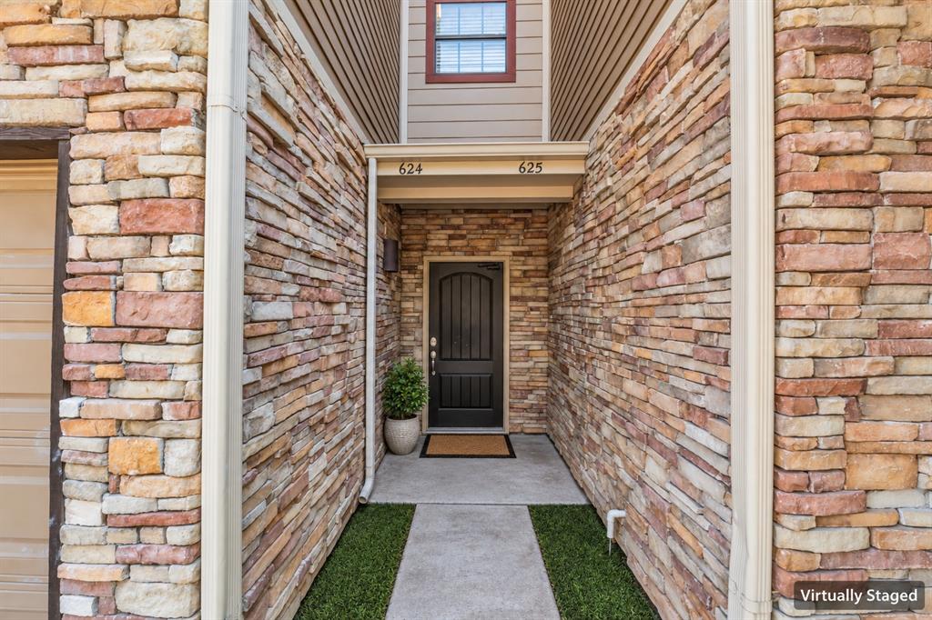 Stacked-stone exterior facade featuring a covered entryway, arched panel door, and concrete walkway Stacked-stone exterior facade featuring a covered entryway, arched panel door, and concrete walkway