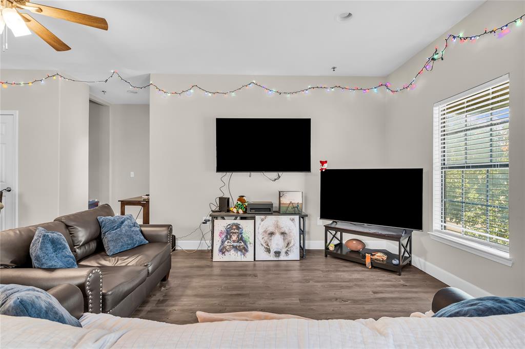 Living area featuring wood-finish flooring, neutral wall paint, and a window with horizontal blinds