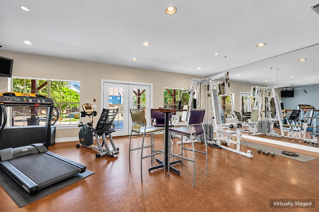 Fitness center featuring high-gloss resilient flooring, wall-to-wall mirrored surfacing, recessed ceiling lighting, and multiple windows providing natural illumination