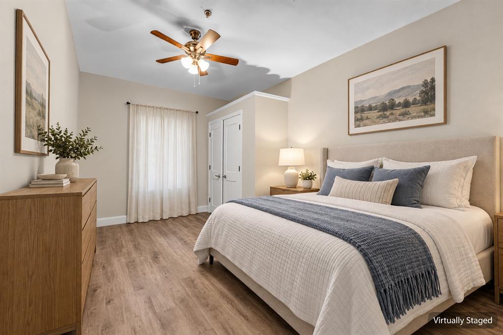 Wood-finish flooring, neutral wall tones, multi-light ceiling fan, and built-in closet with paneled doors