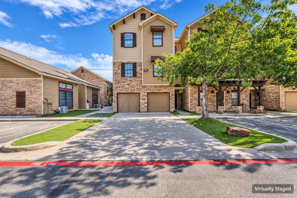 Three-story exterior featuring stone veneer, lap siding, two-car garage, and a timber-frame covered entryway