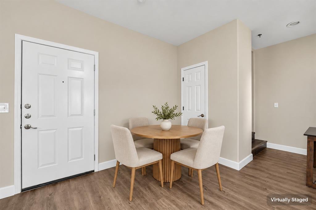 Wood-finish flooring, white paneled entry door with metallic hardware, and white interior doors with traditional molding