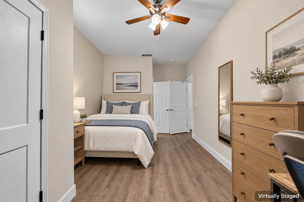 Room featuring wood-finish flooring, a ceiling fan with integrated lighting, and a double-door closet