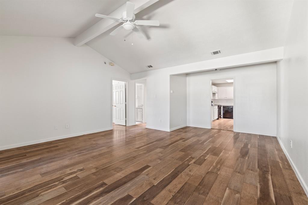 Vaulted ceilings featuring a white beam, wood-finish flooring, and a white ceiling fan with integrated lighting