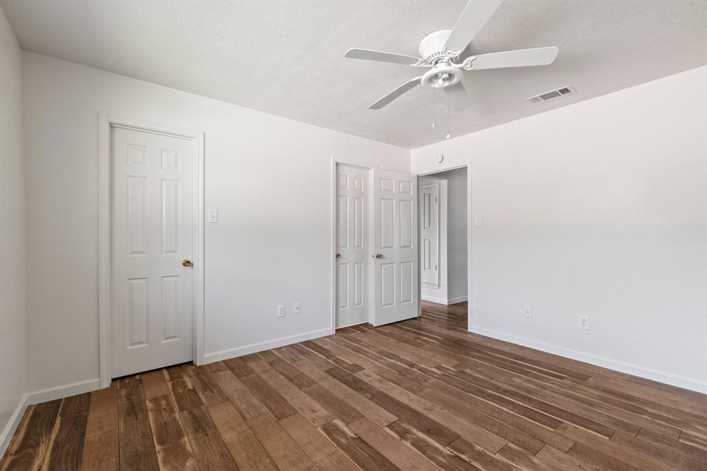 Wood-finish flooring, white paneled interior doors, and a ceiling-mounted fan with integrated lighting