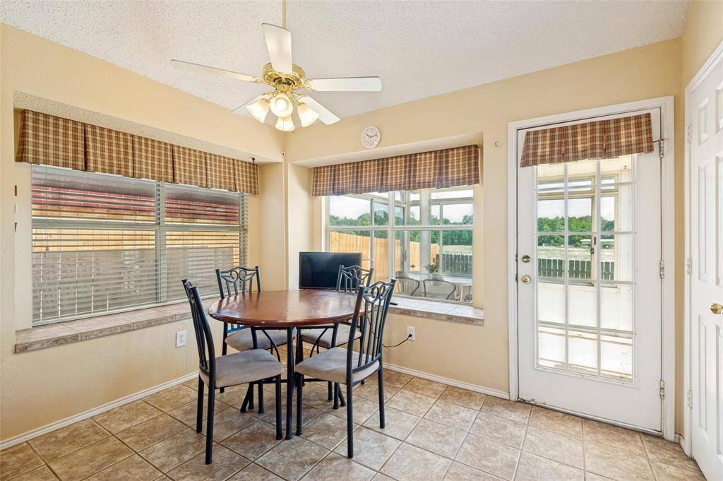 Sun-filled dining area featuring tile flooring, a wrap-around bay window, and a glass-paneled exterior door
