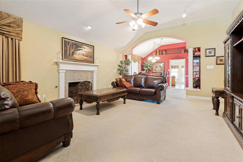 Vaulted ceilings, fireplace with a decorative mantel, arched architectural detail, and neutral carpeting Vaulted ceilings, fireplace with a decorative mantel, arched architectural detail, and neutral carpeting