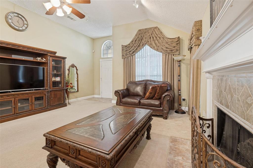Vaulted ceilings, built-in wooden cabinetry, arched window detailing, and a fireplace with tile surround