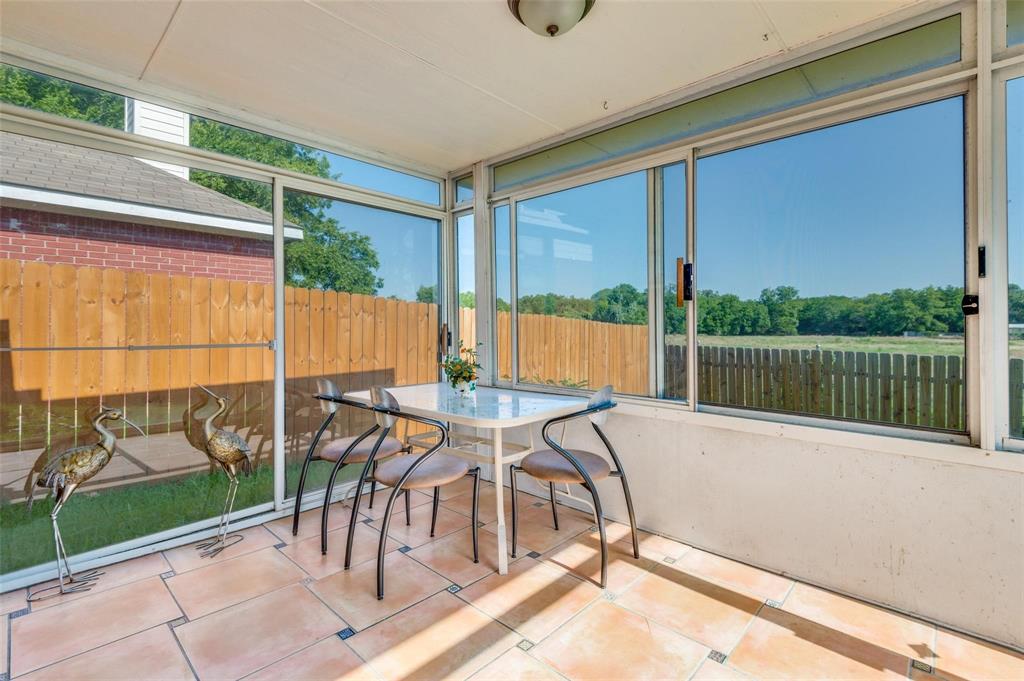 Enclosed sunroom featuring large-pane sliding glass windows, ceramic tile flooring, and a ceiling-mounted light fixture