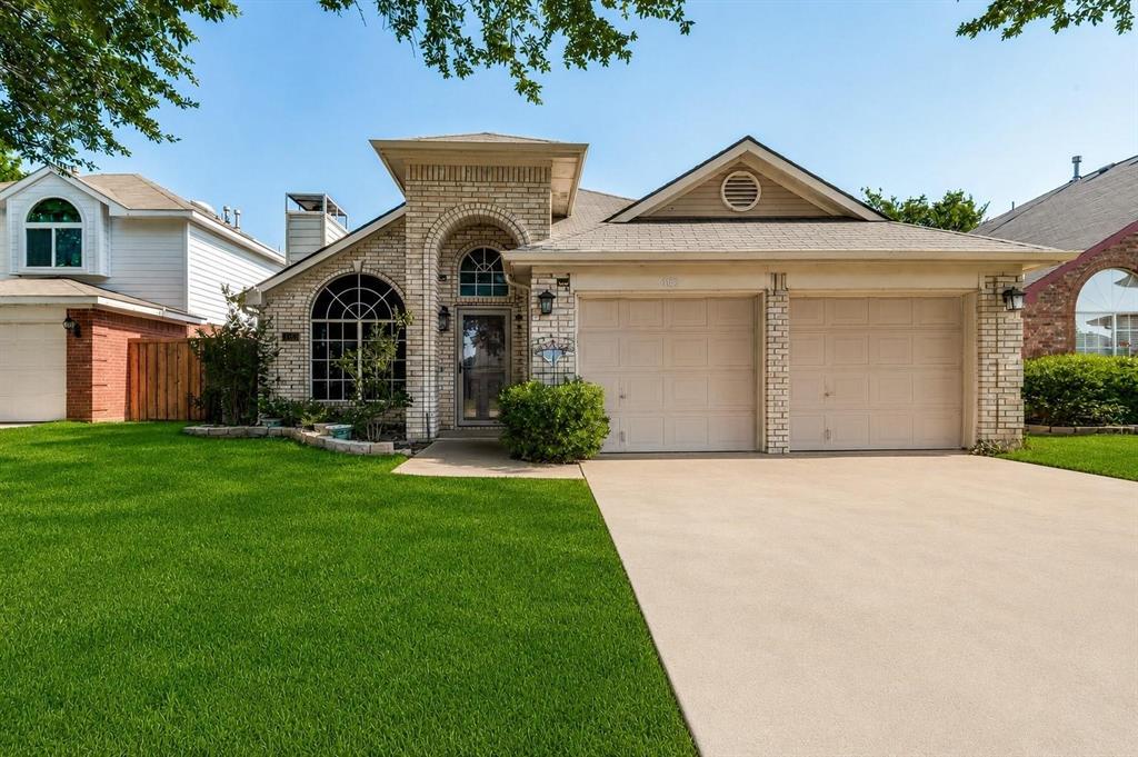 Brick exterior featuring an arched entryway, decorative transom windows, a dual-car garage, and a concrete driveway