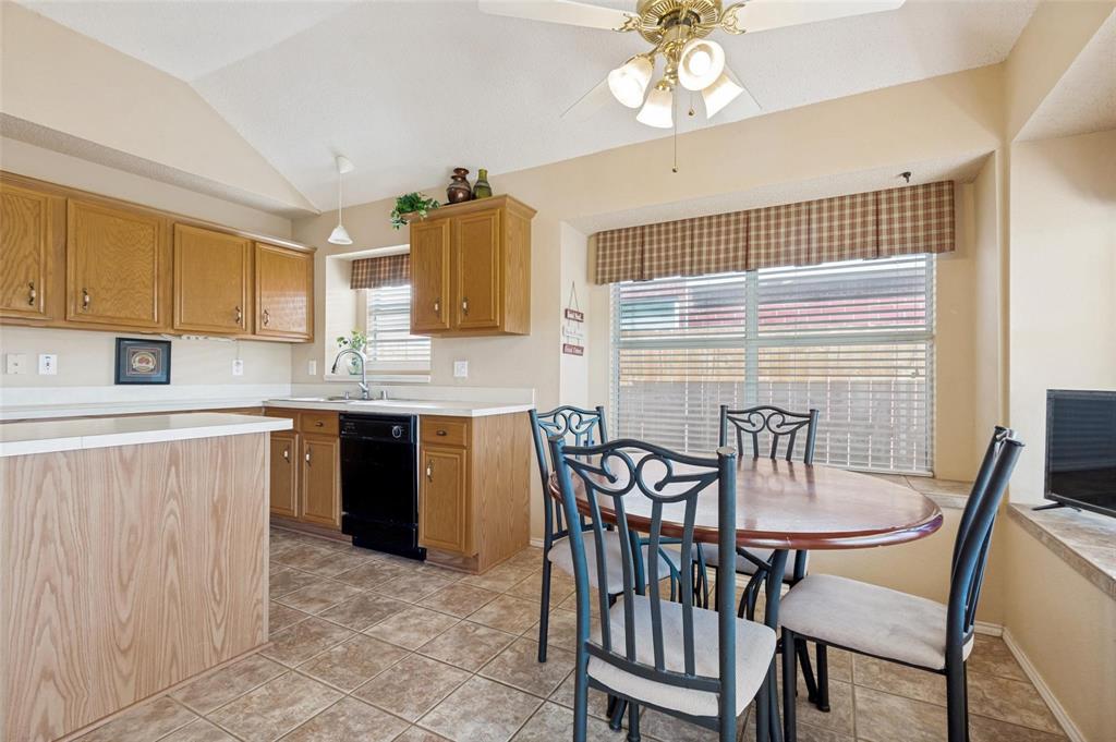 Kitchen featuring wood cabinetry, tile flooring, vaulted ceilings, and a built-in peninsula with a breakfast nook Kitchen featuring wood cabinetry, tile flooring, vaulted ceilings, and a built-in peninsula with a breakfast nook