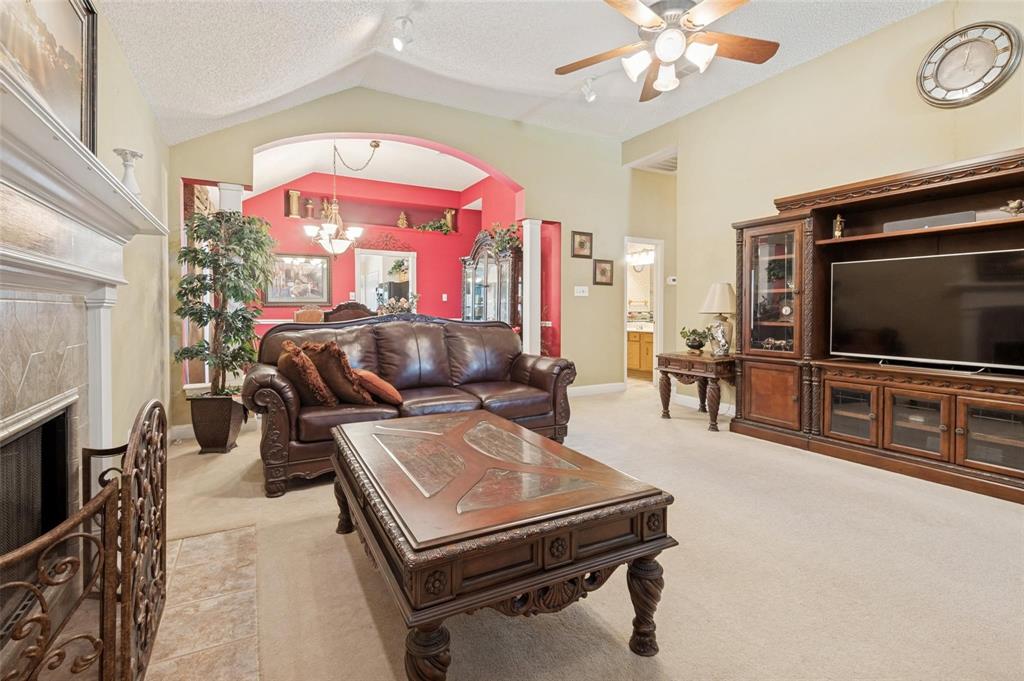 Living area featuring a vaulted ceiling, floor-to-ceiling stone-surround fireplace, and large built-in media cabinetry Living area featuring a vaulted ceiling, floor-to-ceiling stone-surround fireplace, and large built-in media cabinetry
