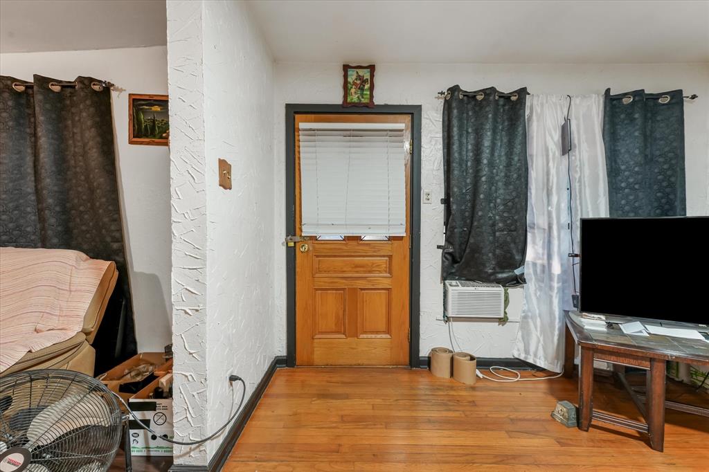 Solid wood door with integrated blinds, textured wall finish, and hardwood flooring Solid wood door with integrated blinds, textured wall finish, and hardwood flooring