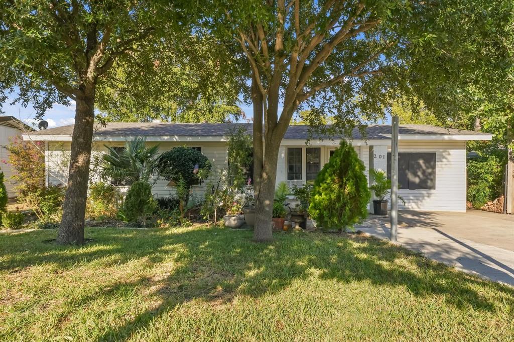 Single-story residence featuring horizontal siding, a composition shingle roof, mature landscaping, and a paved driveway Single-story residence featuring horizontal siding, a composition shingle roof, mature landscaping, and a paved driveway