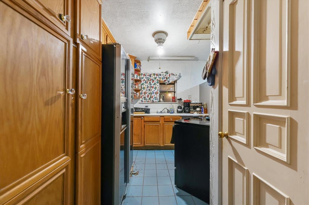 Kitchen featuring natural wood cabinetry, tile flooring, and a stainless steel refrigerator