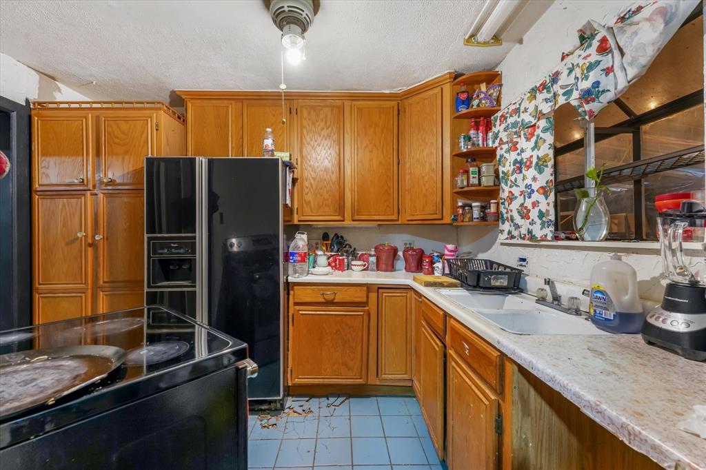 Kitchen featuring wooden cabinetry, solid surface countertops, a dual-basin drop-in sink, and tile flooring Kitchen featuring wooden cabinetry, solid surface countertops, a dual-basin drop-in sink, and tile flooring