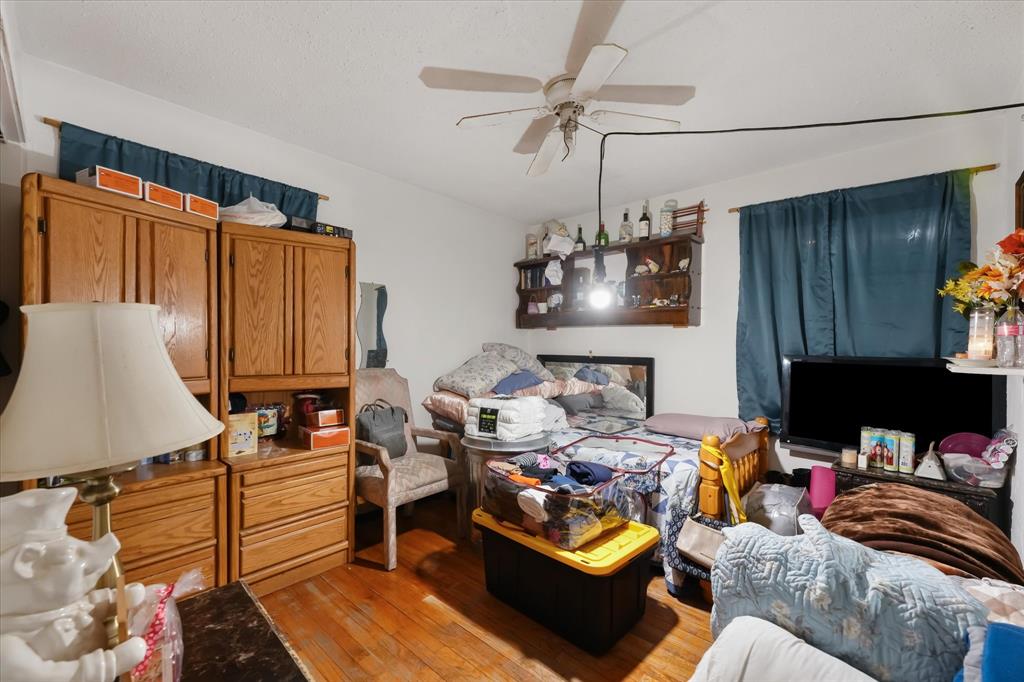 Room featuring wood-finish flooring, built-in wooden cabinetry, a wall-mounted wooden display shelf, and a ceiling fan with light fixture Room featuring wood-finish flooring, built-in wooden cabinetry, a wall-mounted wooden display shelf, and a ceiling fan with light fixture
