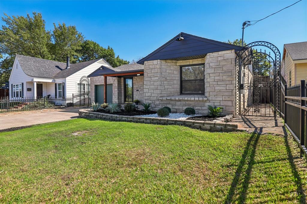 Stone veneer exterior, dark-colored roof, decorative wrought iron gate, front planter box with landscaping, paved driveway Stone veneer exterior, dark-colored roof, decorative wrought iron gate, front planter box with landscaping, paved driveway