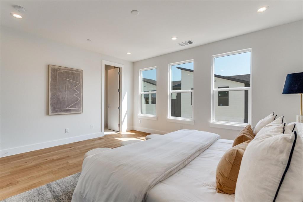 Wood-finish flooring, recessed lighting, and three large windows with white trim