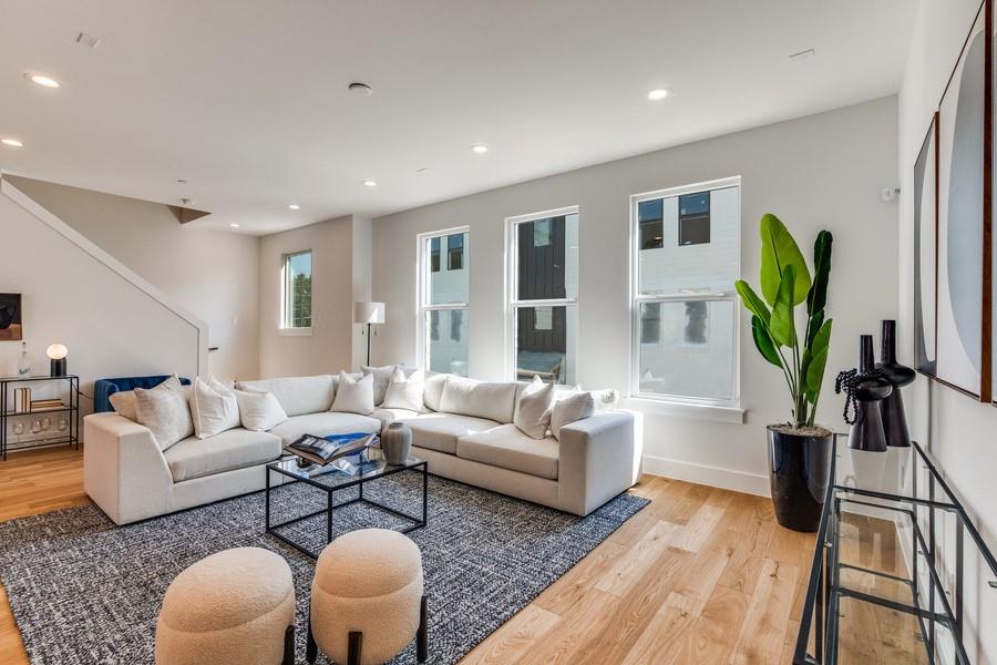 Open-concept interior featuring light wood-finish flooring, recessed lighting, and three tall vertical windows