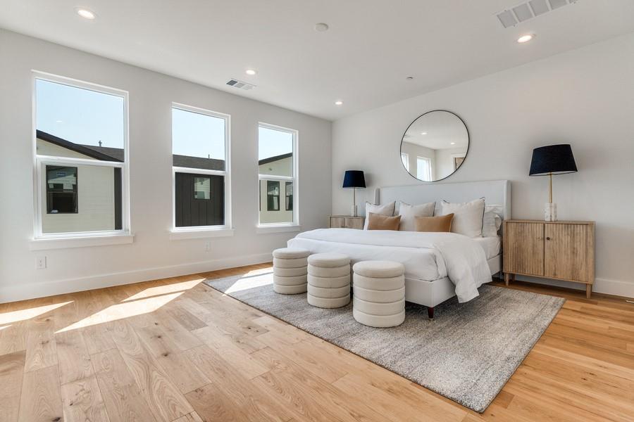 Spacious room featuring wood-finish flooring, recessed lighting, and three tall windows