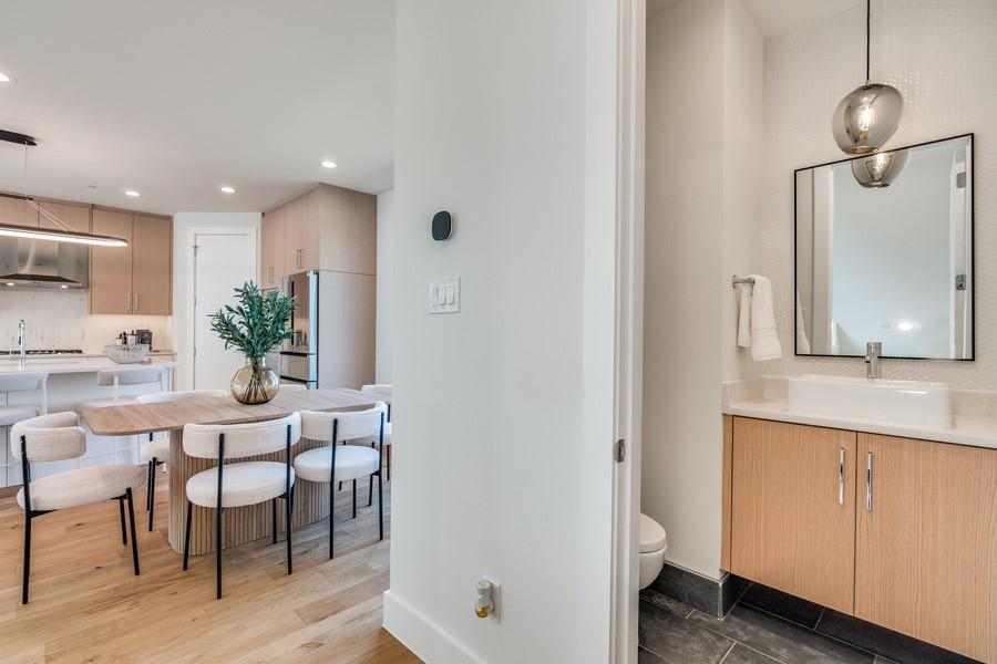 Bathroom featuring a floating wood-finish vanity, rectangular vessel sink, geometric mirror, and pendant lighting, complemented by wood-finish flooring and stone-finish floor tile