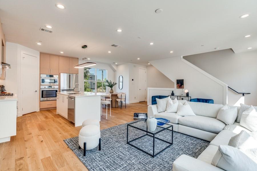 Open-concept living space featuring wood-finish flooring, recessed lighting, and a kitchen island with a neutral countertop