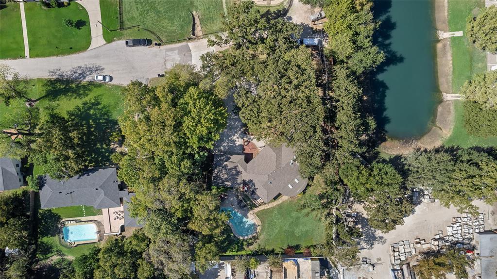 Aerial perspective of a sprawling lot featuring mature trees, a private inground swimming pool, and direct water frontage